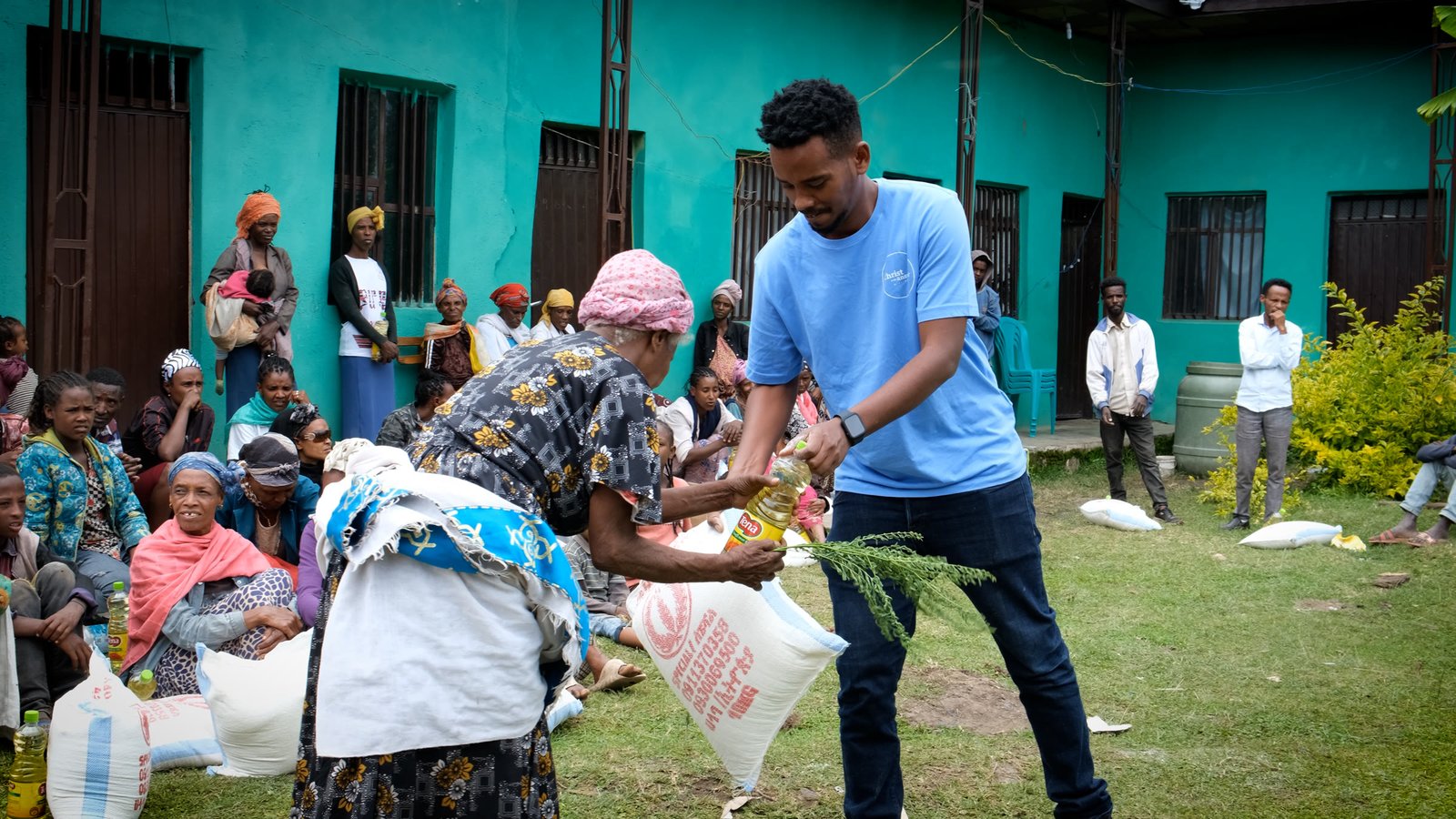 A CITA team member handing cooking oil and a food sack to a woman.