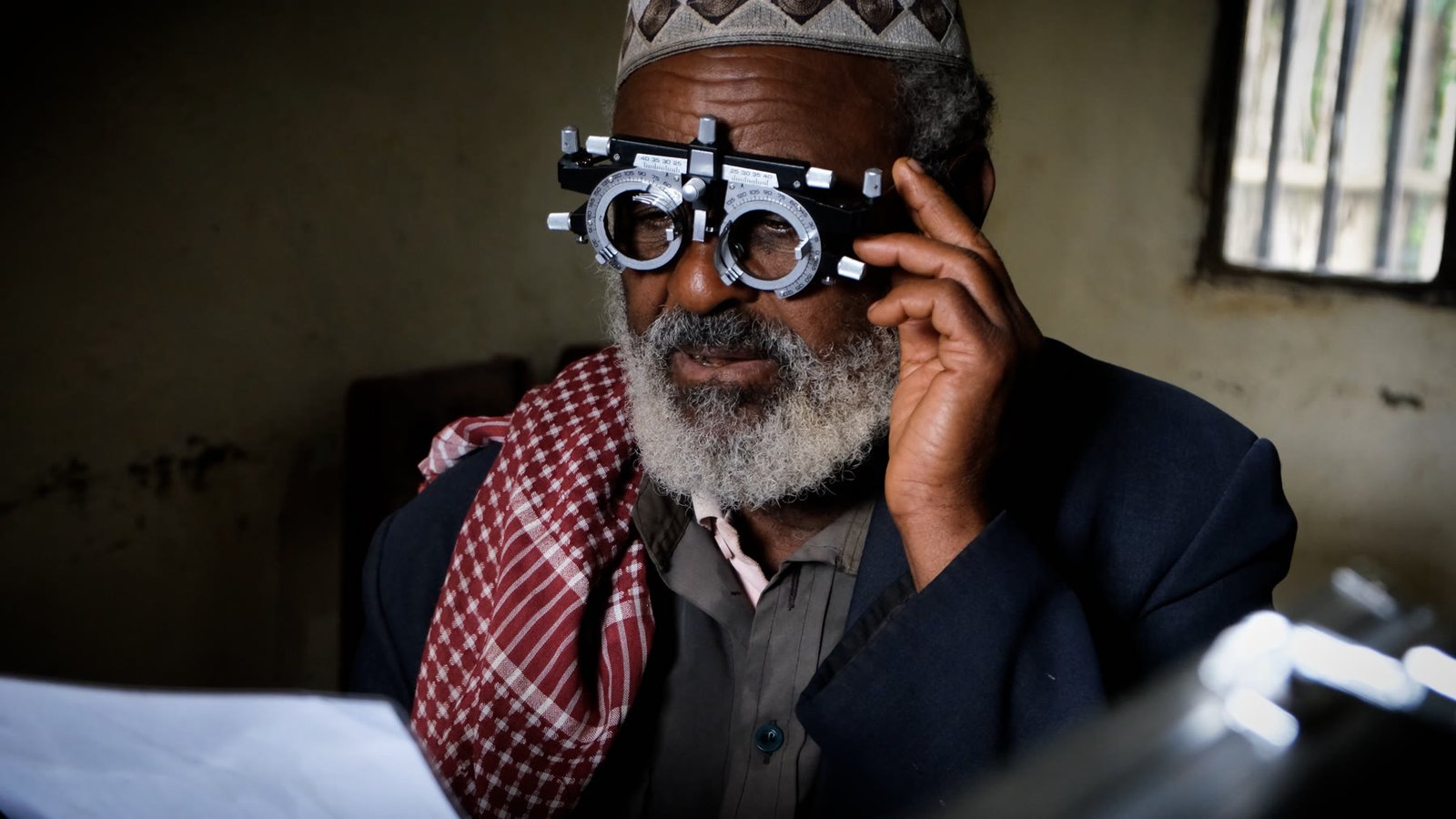 An older man wearing a trial lens frame during an eye examination.